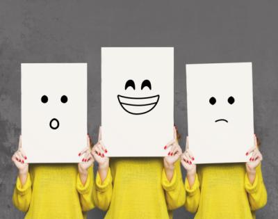 people holding papers in front of their faces showing different emotions