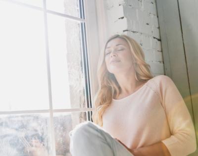 woman sitting in the light of a window looking relaxed