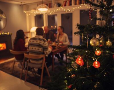 Family sitting at dinner table in background of a Christmas tree