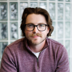 A male therapist with glasses wearing a red pullover