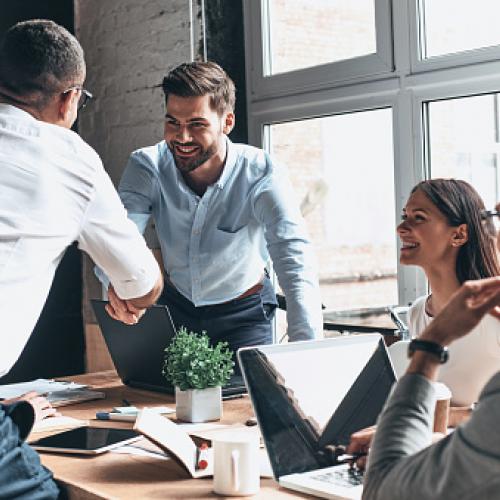 Coworkers shaking hands at table